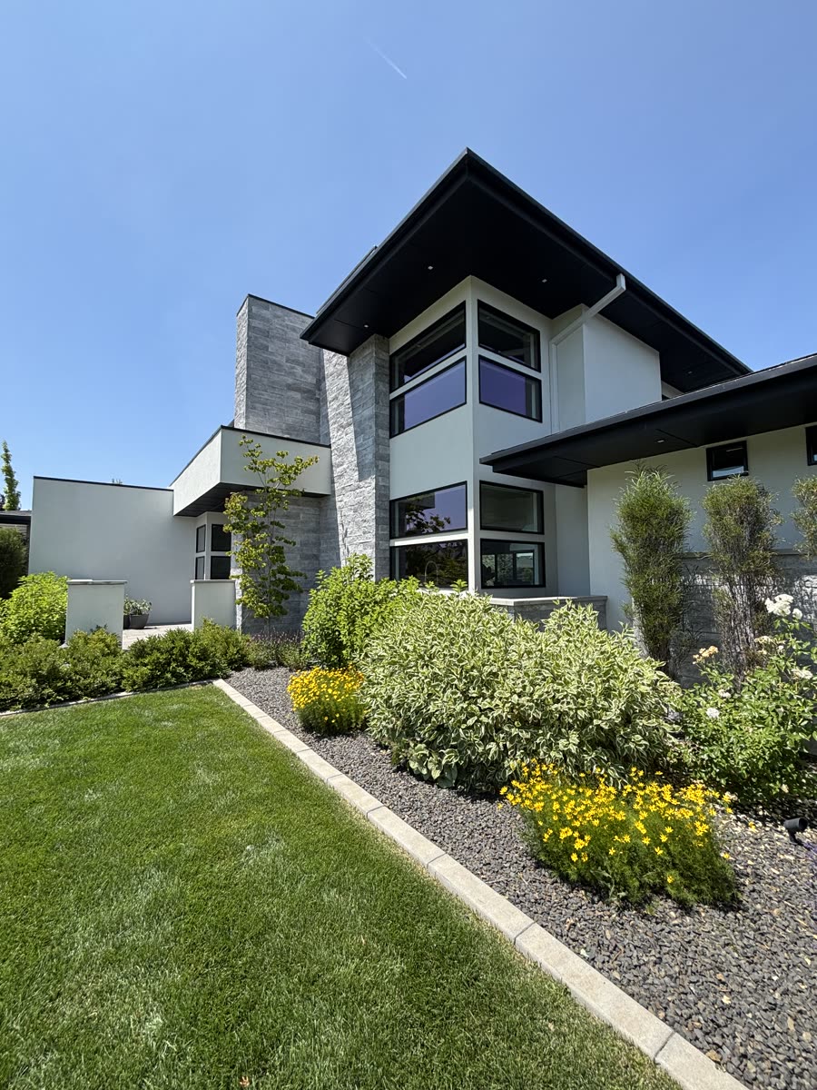A modern Eagle home with tall upper-story glass behind established landscaping
