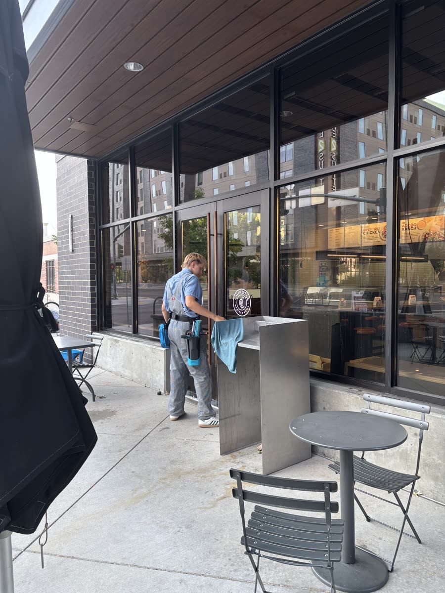 A Seymour's technician cleaning storefront glass at a downtown Boise restaurant