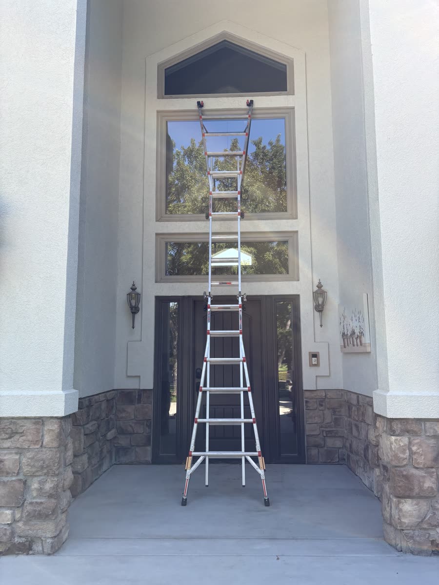 A ladder set at a home's front entry to reach the tall windows above the door