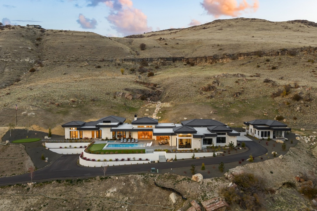 A foothills home above the Boise valley, lit at dusk through its windows