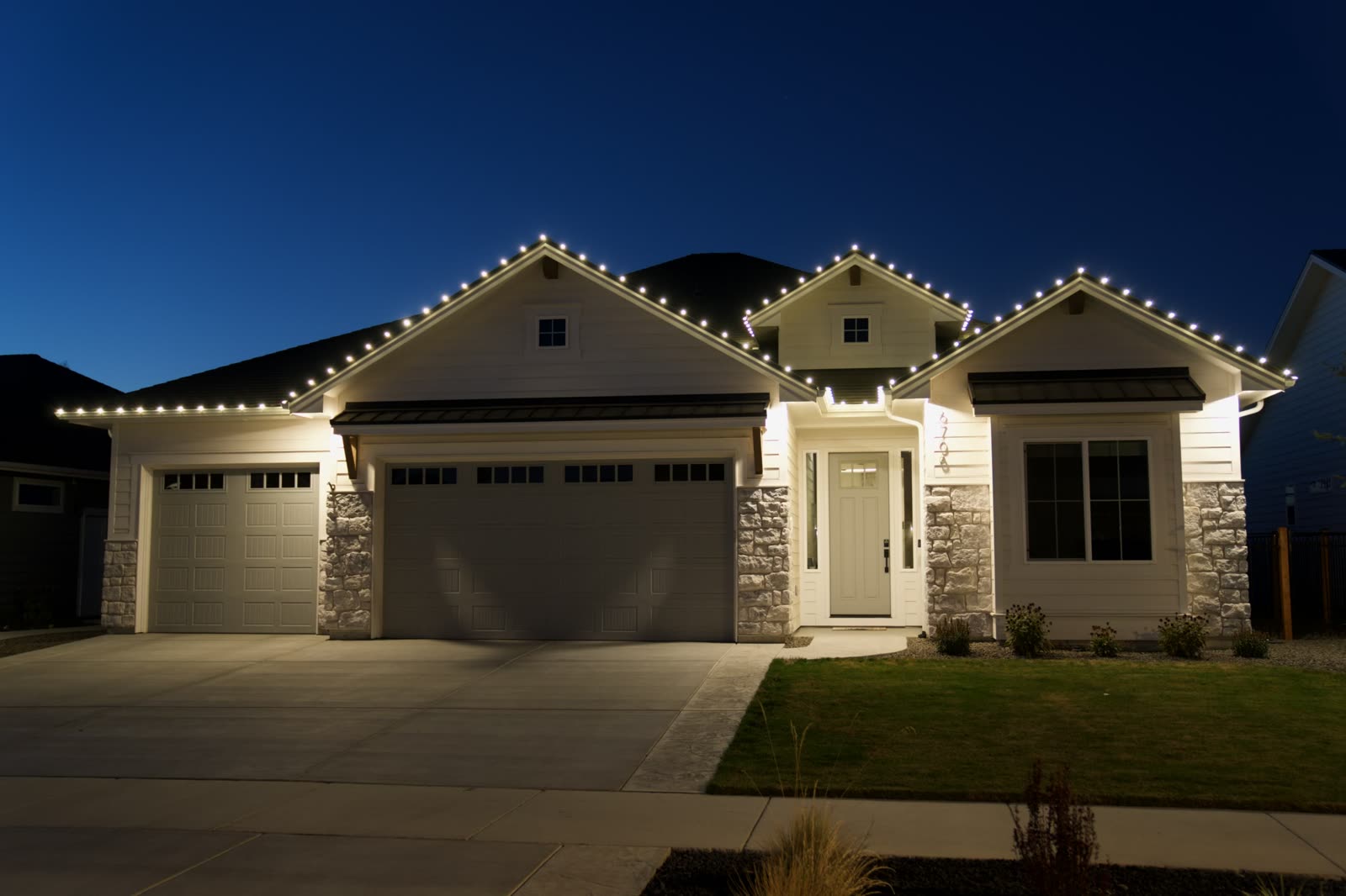 A Boise home at twilight with warm white lights running the length of every roofline and gable